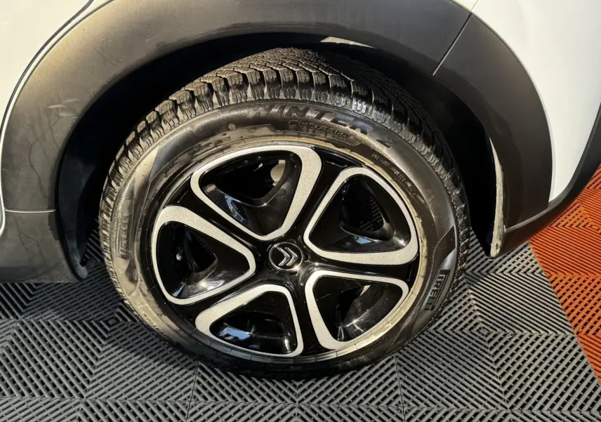 Gros plan sur la roue arrière droite blanche d'une Citroën C3 2024 avec jante noire et argentée au design distinctif.