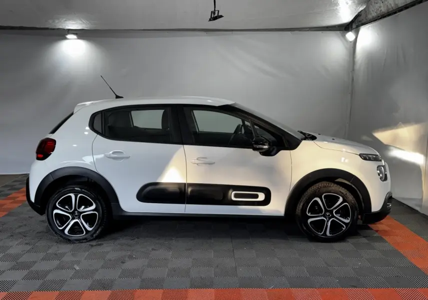 Citroën C3 blanche vue de profil côté gauche, avec protections noires distinctives sur les portières.