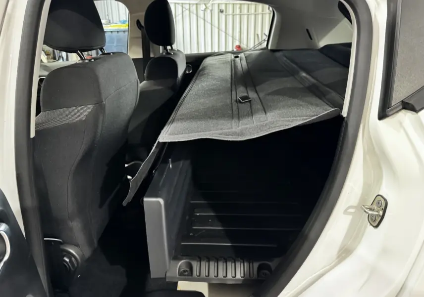 Vue intérieure arrière côté droit d'une Citroën C3 blanche 2024, coffre ouvert avec cache-bagages partiellement relevé.