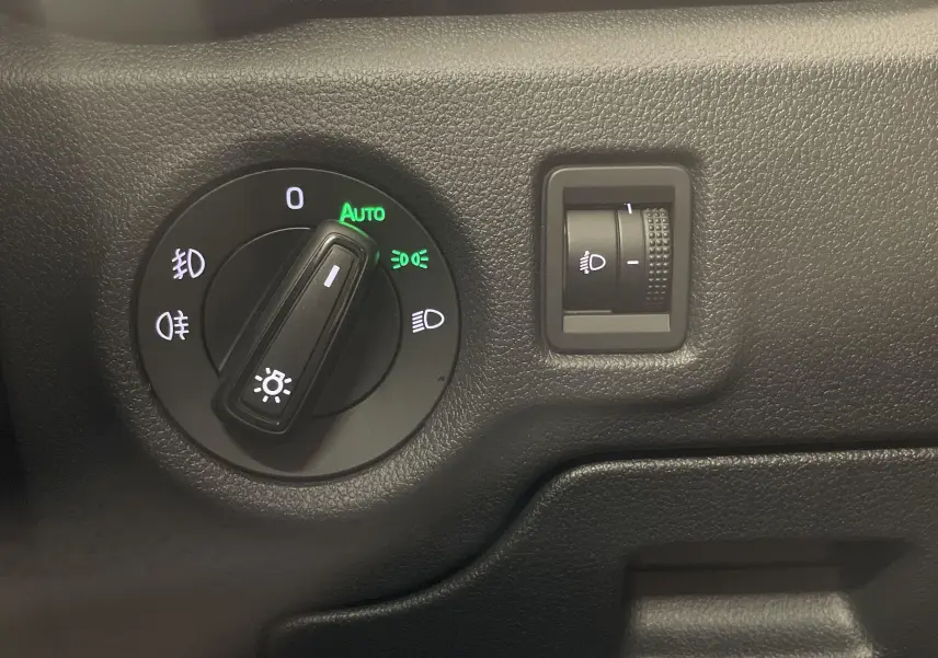 Gros plan sur le bouton de réglage des phares avec fonction automatique dans une Skoda Fabia gris argent 2025.