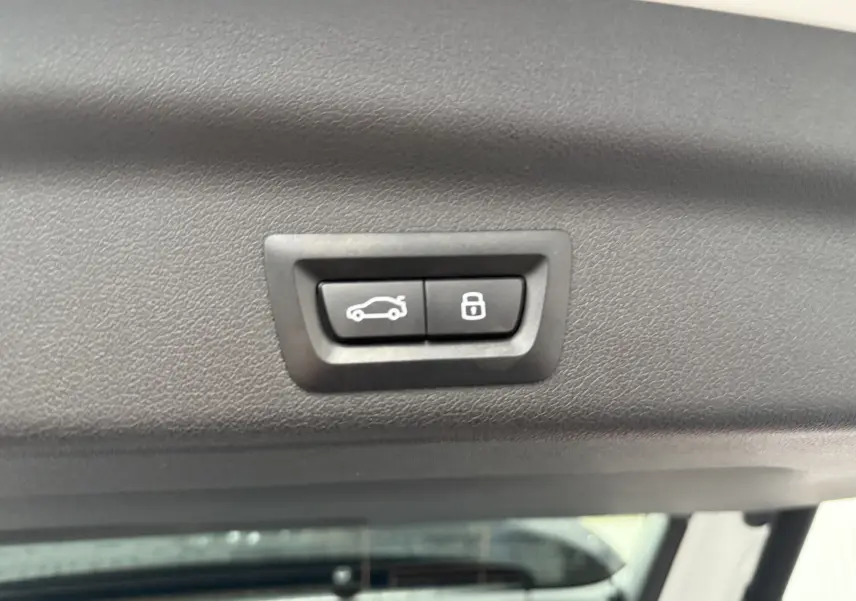 Vue écran multimédia montrant une BMW X1 blanc minéral en 3/4 arrière droit avec aides au stationnement activées.