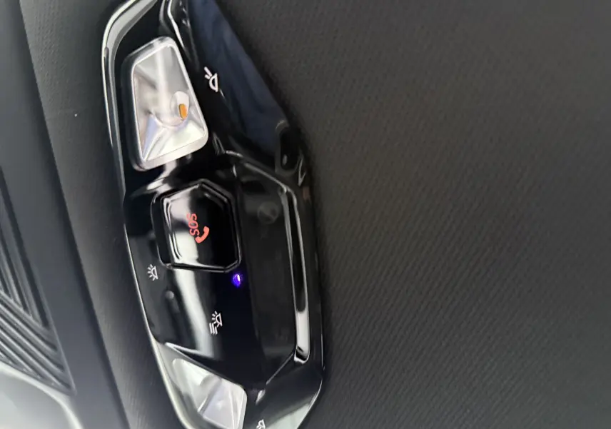 Gros plan sur la console centrale du BMW X1 20D 2025, avec porte-gobelets et surface noire brillante à motifs.