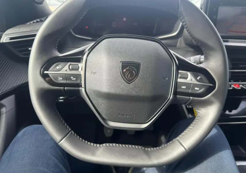 Vue rapprochée du volant noir de la Peugeot 2008 2024, avec commandes intégrées et logo lion central.