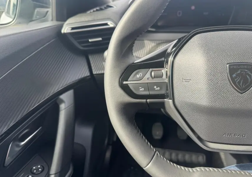 Vue intérieure côté conducteur du Peugeot 2008 blanc 2024, volant multifonction et tableau de bord moderne.