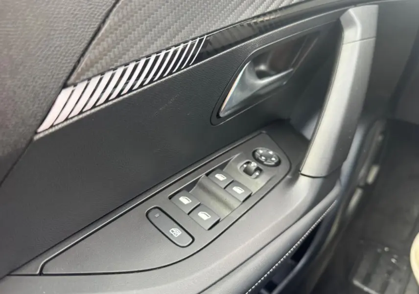 Vue rapprochée de la porte côté gauche du Peugeot 2008 blanc 2024, avec commandes des vitres électriques et rétroviseurs.