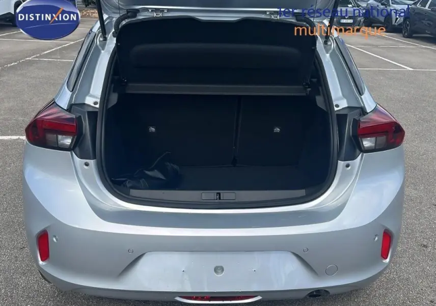 Vue arrière d'une Opel Corsa gris clair 2025 avec coffre ouvert, feux arrière allumés et capot de coffre relevé.