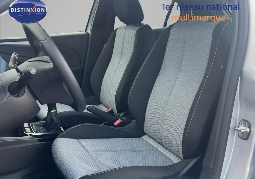 Vue intérieure côté conducteur de l’Opel Corsa gris 2025, montrant les sièges avant en tissu bicolore et la boîte manuelle.