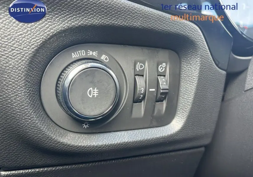 Gros plan sur le bouton de commande des phares et réglages lumineux dans l'habitacle de l'Opel Corsa gris.