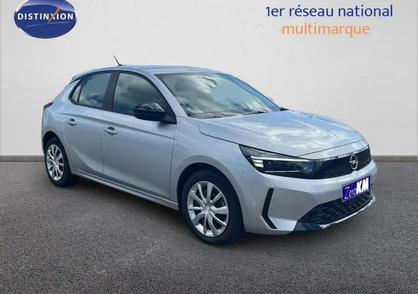 Vue 3/4 avant d'une Opel Corsa gris clair 2025 avec phares LED et jantes alliage, stationnée sur sol gris.