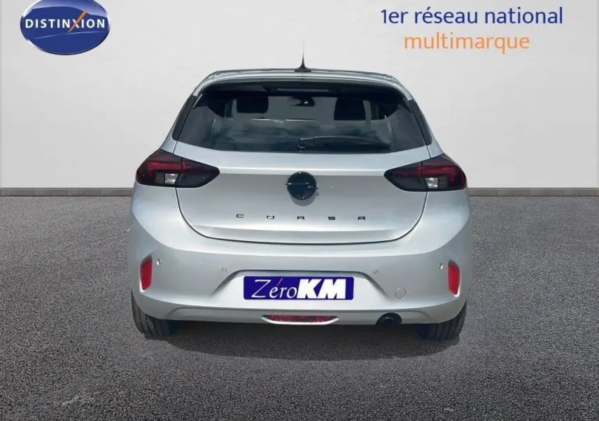 Vue arrière d'une Opel Corsa gris clair 2025 avec feux arrière foncés et logo central sur un fond neutre.