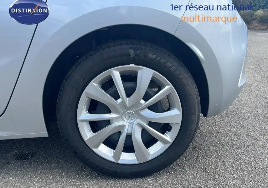 Gros plan sur la roue avant gauche grise d'une Opel Corsa 2025 avec jante alliage et logo Opel au centre.