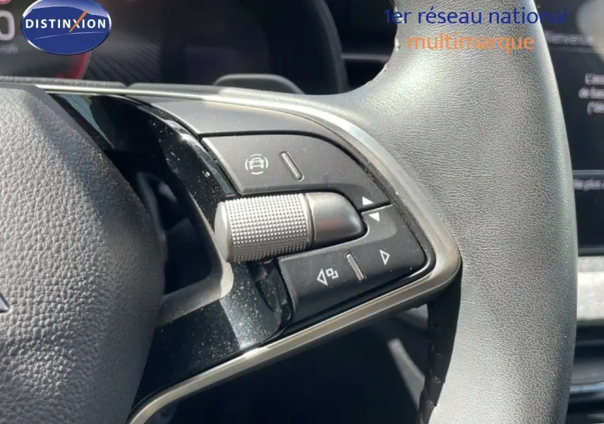 Gros plan sur les commandes gauche du volant en cuir gris d'une Skoda Scala blanche Glacier 2025.