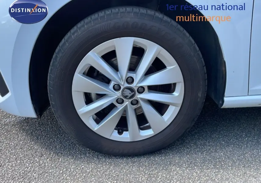 Gros plan sur la roue avant droite d'une Skoda Scala blanc glacier avec jante alliage et logo central visible.