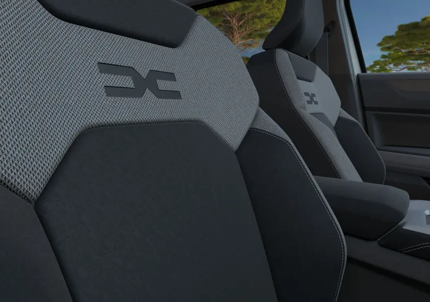Gros plan sur les sièges avant gris et noirs du Dacia Bigster Hybrid 155 Journey avec logo distinctif brodé.