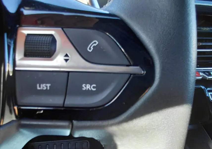 Gros plan sur les commandes au volant du Peugeot 2008 Hybrid 136 e-DCS6 Style, intérieur noir avec détails argentés.