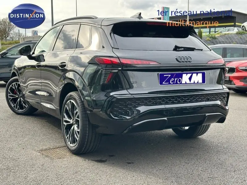 Audi Q3 2.0 TDI noir métallisé vue 3/4 arrière droit, jantes alu noires et feux arrière LED allumés.
