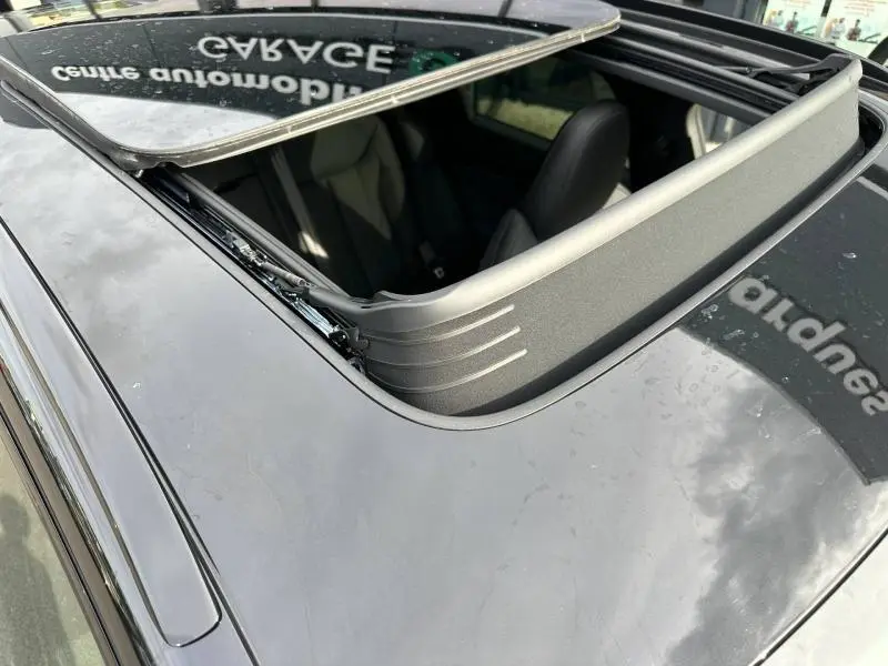 Vue plongeante sur le toit ouvrant ouvert d'un Audi Q3 noir Mythique métallisé, montrant l'intérieur des sièges avant.