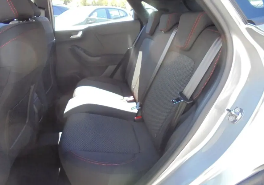 Vue côté droit de l'habitacle arrière du Ford Puma gris Solar Metal avec sièges tissu noir et surpiqûres rouges.