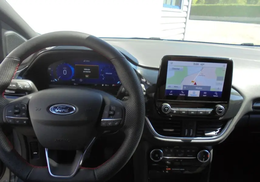 Vue intérieure centrée sur le volant et l'écran tactile du Ford Puma gris Solar Metal 2022 avec navigation affichée.