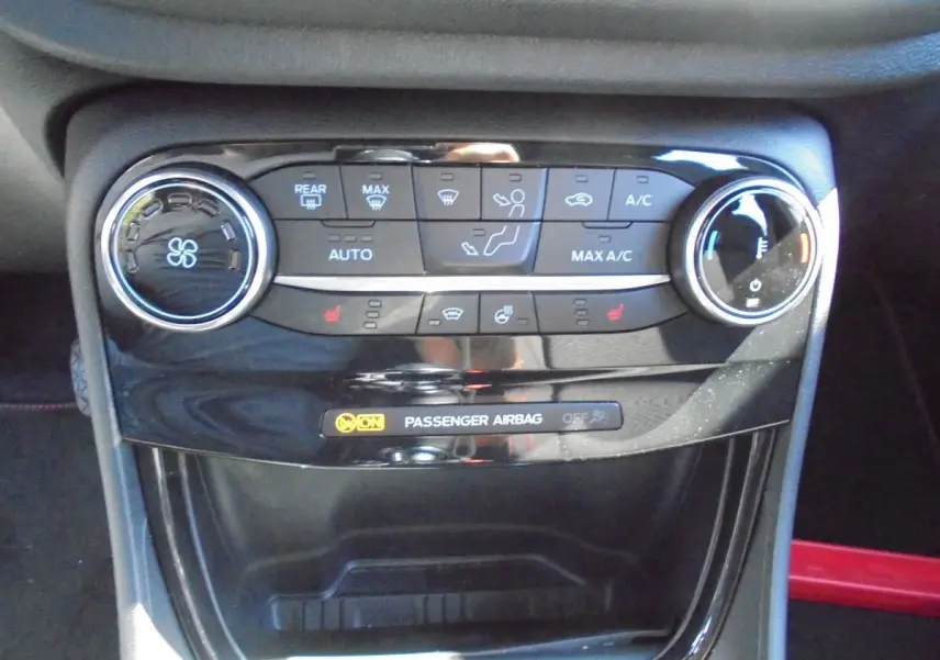 Gros plan sur la console centrale du Ford Puma 2022, mettant en valeur les commandes de climatisation et l'indicateur d'airbag passager.