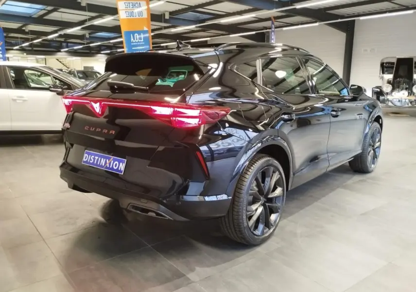 Vue 3/4 arrière droite d'une CUPRA Formentor noire métal avec feux arrière en bandeau lumineux Tri-LED et jantes alliage 19''.