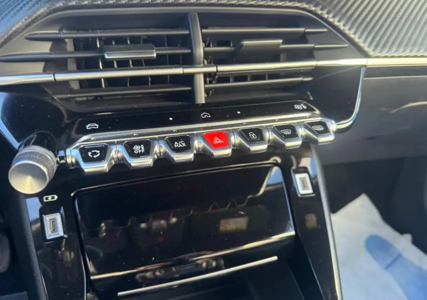 Vue rapprochée de la console centrale noire du Peugeot 2008 Hybrid 136 e-DCS6 Allure avec boutons de commande et aérateurs.