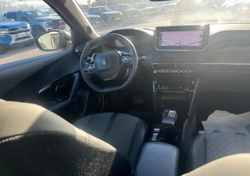 Intérieur du Peugeot 2008 Hybrid 136 Allure vu de l'arrière, montrant le volant, l'écran tactile et la console centrale noire.