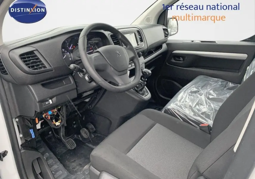 Vue intérieure côté conducteur du Peugeot Expert Fourgon 2023, tableau de bord noir avec volant et siège plastique.