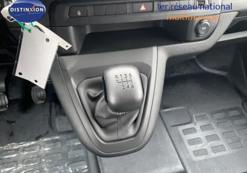 Gros plan sur le levier de vitesses manuel gris du Peugeot Expert Fourgon blanc, avec tableau de bord et pédales visibles.