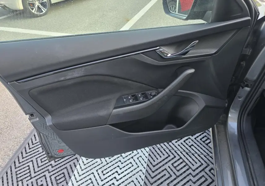 Vue intérieure côté gauche de la porte avant gris graphite métal de la Skoda Scala avec commandes des vitres et poignée chromée.