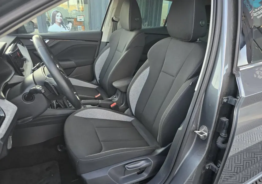 Vue intérieure côté conducteur de la Skoda Scala 2024 gris graphite, sièges tissu noir et gris avec surpiqûres blanches.
