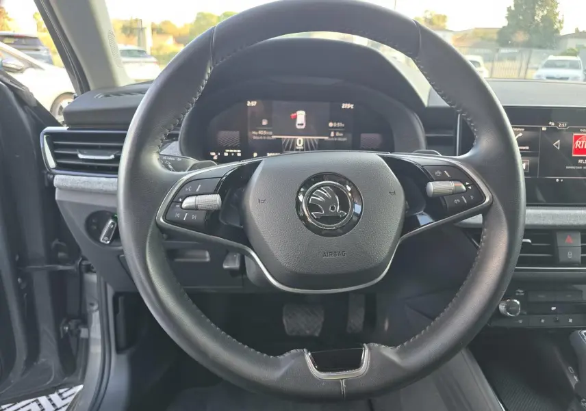 Vue intérieure centrée sur le volant noir de la Skoda Scala 2024 avec tableau de bord digital et écran tactile.