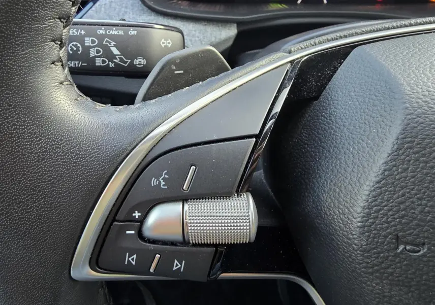 Gros plan sur les commandes multifonctions argentées du volant noir du Skoda Scala gris graphite 2024.