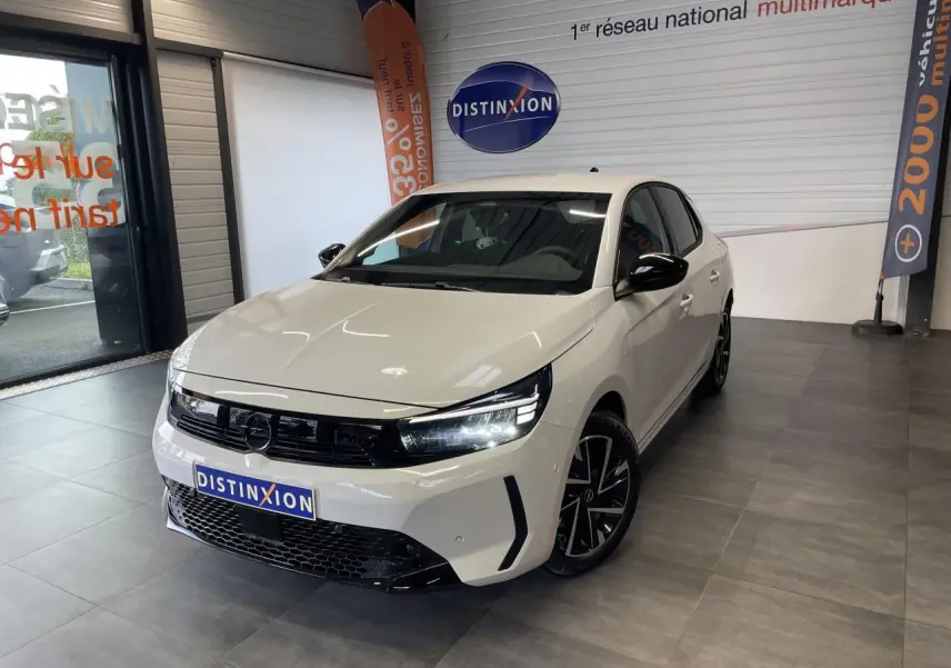 Vue 3/4 avant droite d'une Opel Corsa blanche avec calandre noire et jantes alliage noires diamantées en showroom.