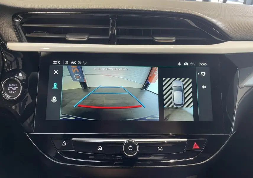 Écran tactile central affichant la caméra de recul panoramique dans l'habitacle noir d'une Opel Corsa blanche.