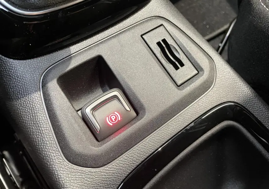 Gros plan sur le frein de parking électrique allumé dans la console centrale noire de l'Opel Corsa 2026.