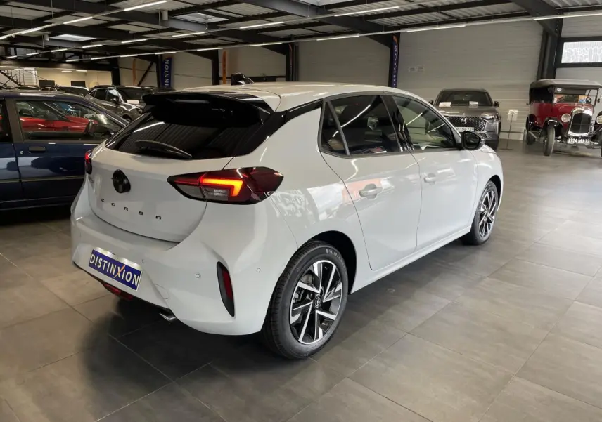 Opel Corsa blanche vue 3/4 arrière droit en intérieur, avec feux arrière LED et jantes alliage diamantées.