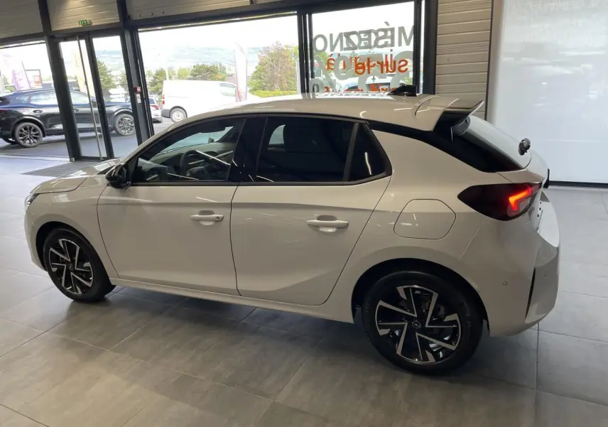 Opel Corsa blanche vue de profil côté gauche, vitres arrière surteintées et jantes alliage noires diamantées.
