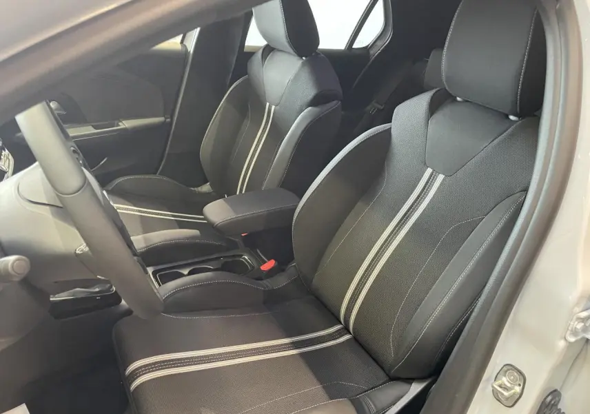 Vue intérieure côté conducteur de l'Opel Corsa blanc, sièges sport noirs avec bandes blanches centrales et accoudoir.