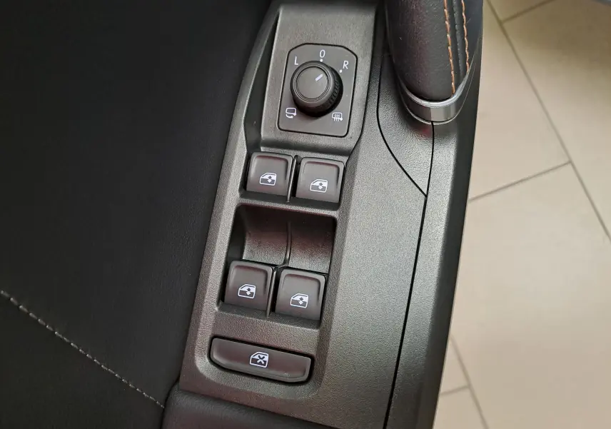 Gros plan sur les commandes des vitres électriques et rétroviseurs côté conducteur d’une CUPRA Leon 2024 finition Gris Magnétique Mat.