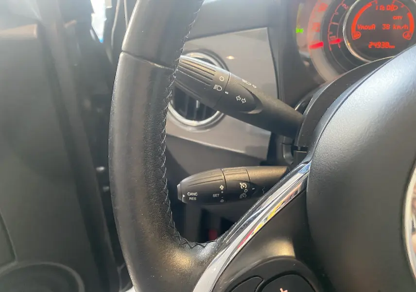 Gros plan sur le volant en cuir noir et les commandes de clignotants de la Fiat 500 Lounge 2019, tableau de bord partiellement visible.