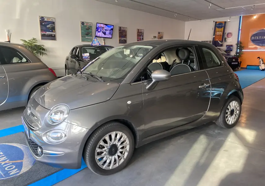 Vue 3/4 avant droite d'une Fiat 500 Lounge gris foncé exposée en showroom avec jantes multibranches.
