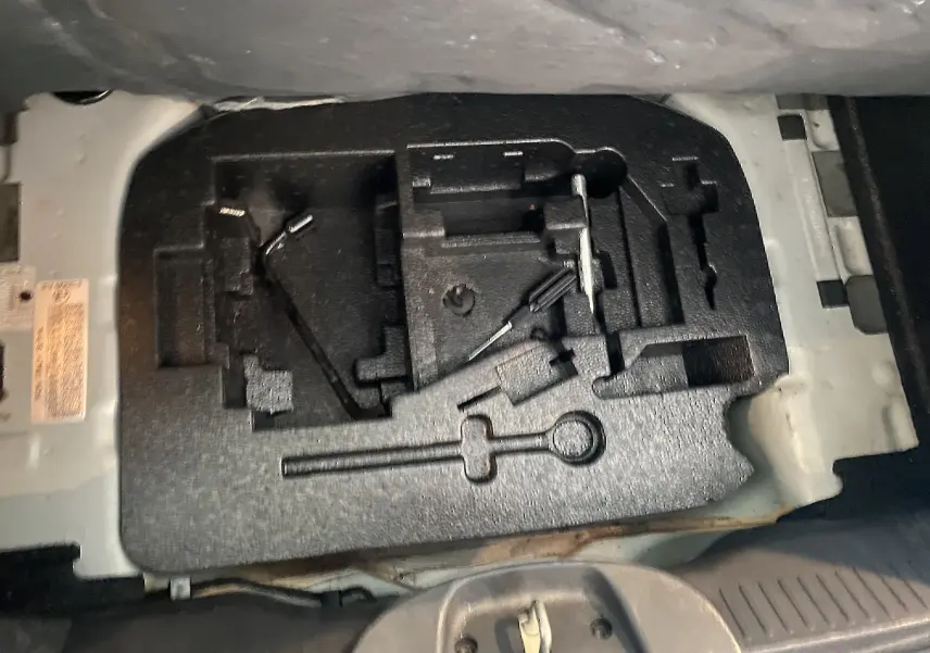 Coffre ouvert montrant le rangement à outils vide du Fiat 500 gris foncé, version 1.2 8V 69 Lounge de 2019.