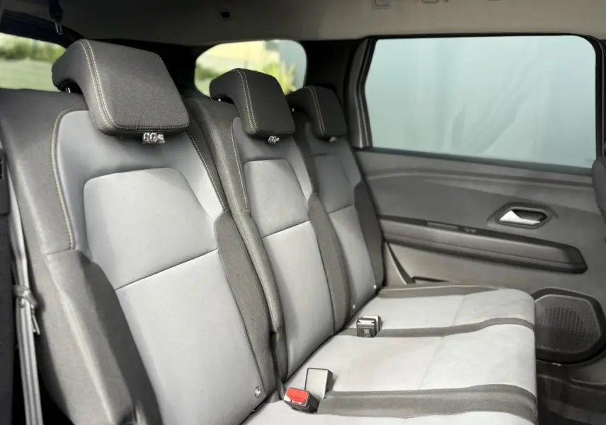 Vue latérale droite des sièges arrière gris clair et foncé du Dacia Jogger 2024 dans un intérieur spacieux.