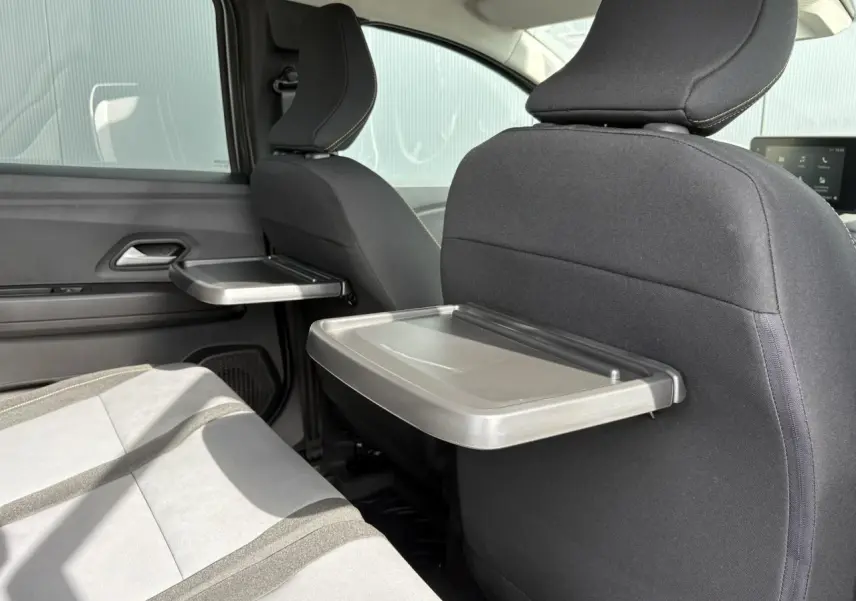 Vue intérieure arrière du Dacia Jogger 2024 avec tablettes aviation déployées sur les dossiers des sièges avant.