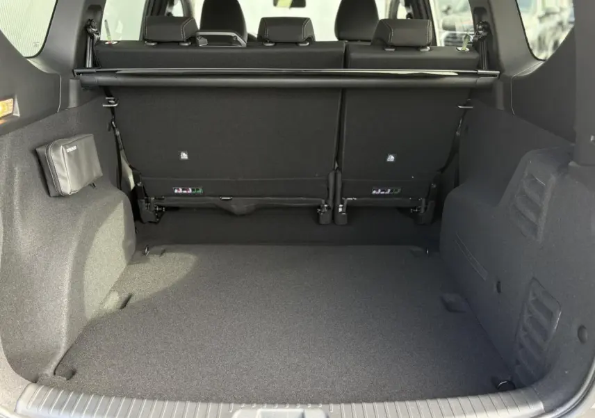 Coffre spacieux du Dacia Jogger ECO-G 100 Extreme+ vu de l'arrière, intérieur noir avec banquette rabattue.
