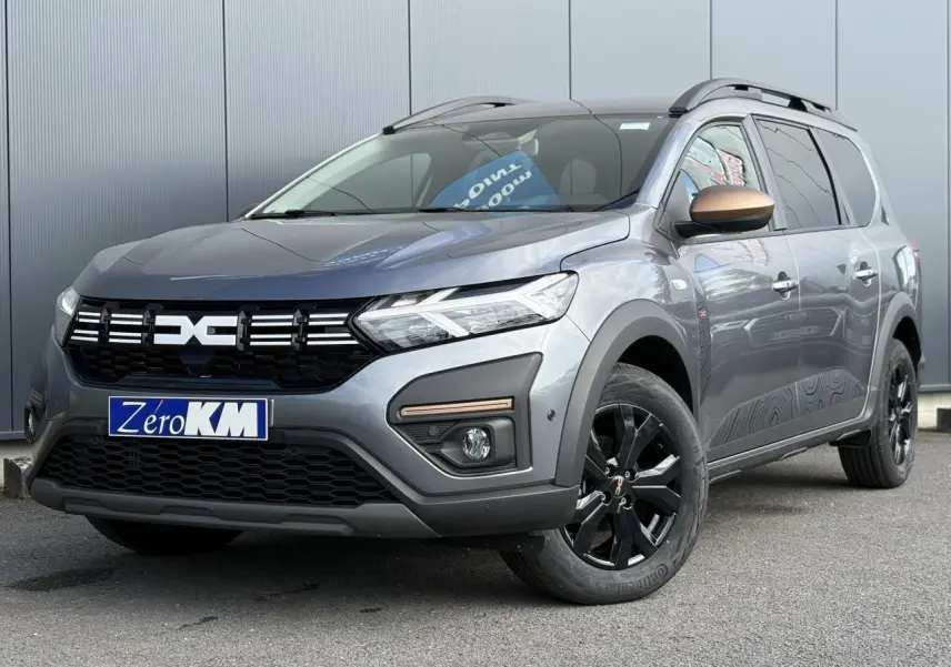 Dacia Jogger Gris Schiste en 3/4 avant droit, avec jantes noires et rétroviseur cuivré distinctif.