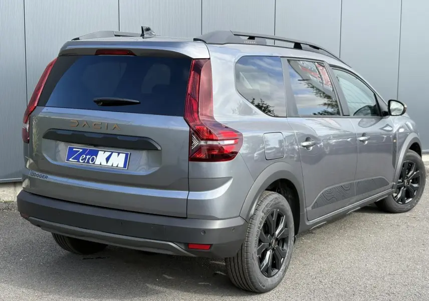 Vue 3/4 arrière droite du Dacia Jogger 2024 Gris Schiste avec jantes noires et barres de toit modulaires.
