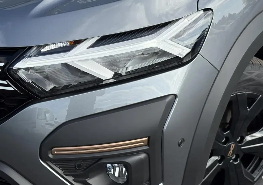 Gros plan sur l'avant droit gris schiste du Dacia Jogger 2024, mettant en valeur le phare LED et la jante noire.