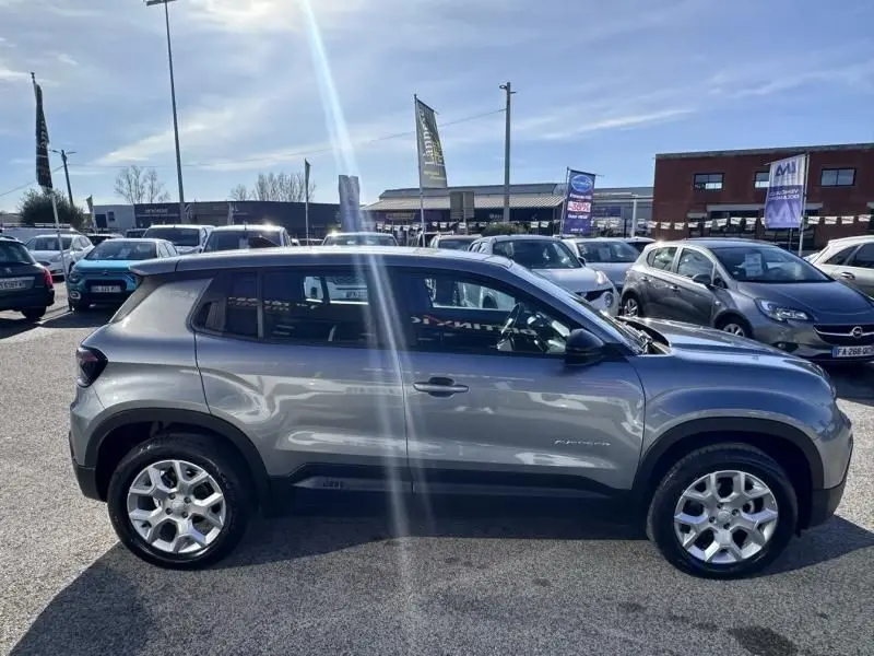 Vue de profil côté gauche d’un Jeep Avenger 2025 gris métallisé avec jantes alliage et toit noir en extérieur.